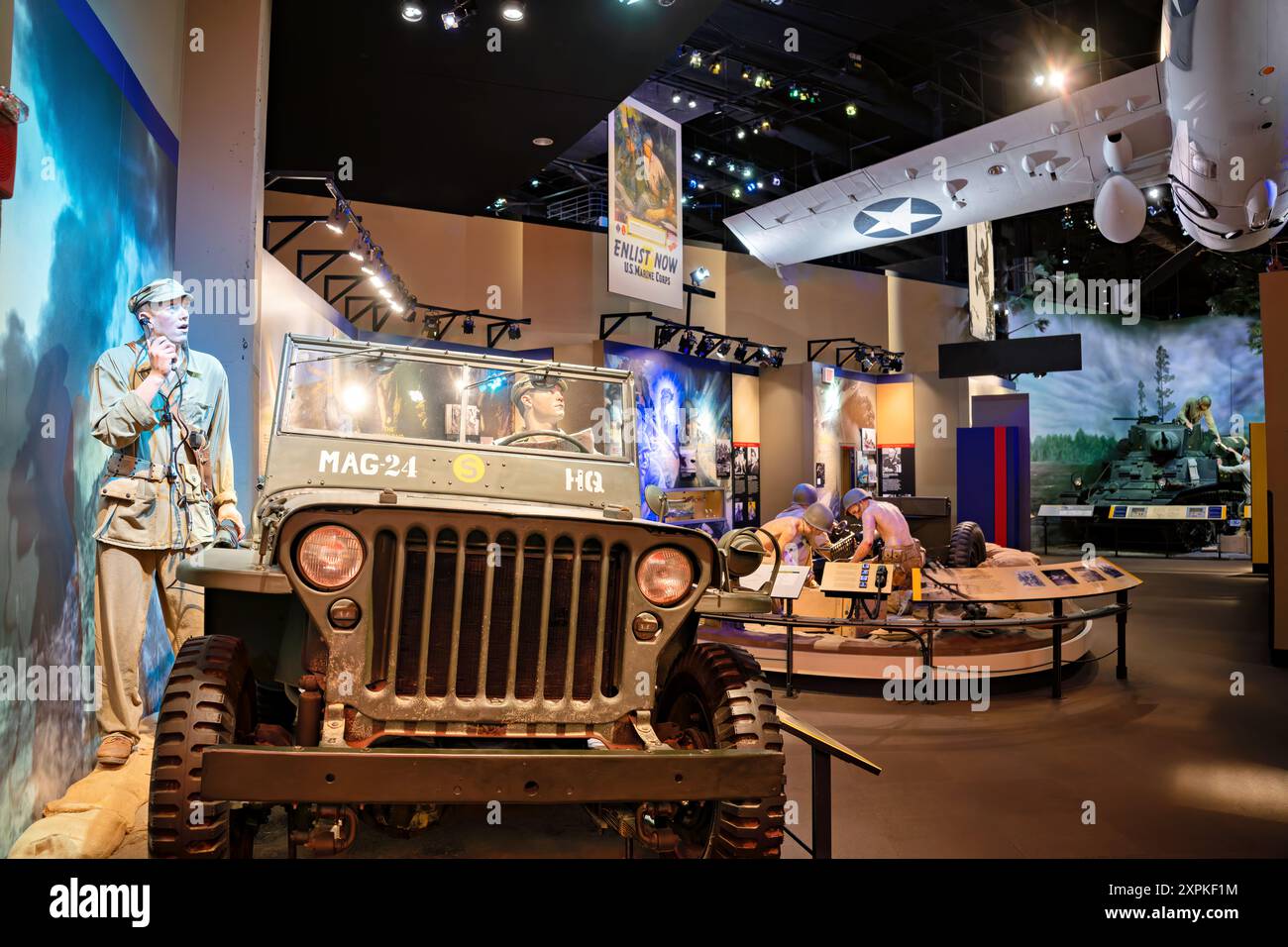 National Museum Of The Marine Corps World War II Exhibit Triangle Virginia | TRIANGLE, Virginia — Una galleria della Seconda Guerra mondiale al National Museum of the Marine Corps ricrea un posto di comando del teatro del Pacifico, con una jeep bellica contrassegnata "MAG-24 HQ" accanto a manichini e un manifesto di reclutamento d'epoca "Enlist Now". Le mostre di questa ala si basano su artefatti tra cui il carro leggero M3A1 Stuart e il cannone anticarro da 37 mm per tracciare le campagne dei Marines su Guadalcanal, Tarawa, Saipan, Iwo Jima e Okinawa. Foto Stock