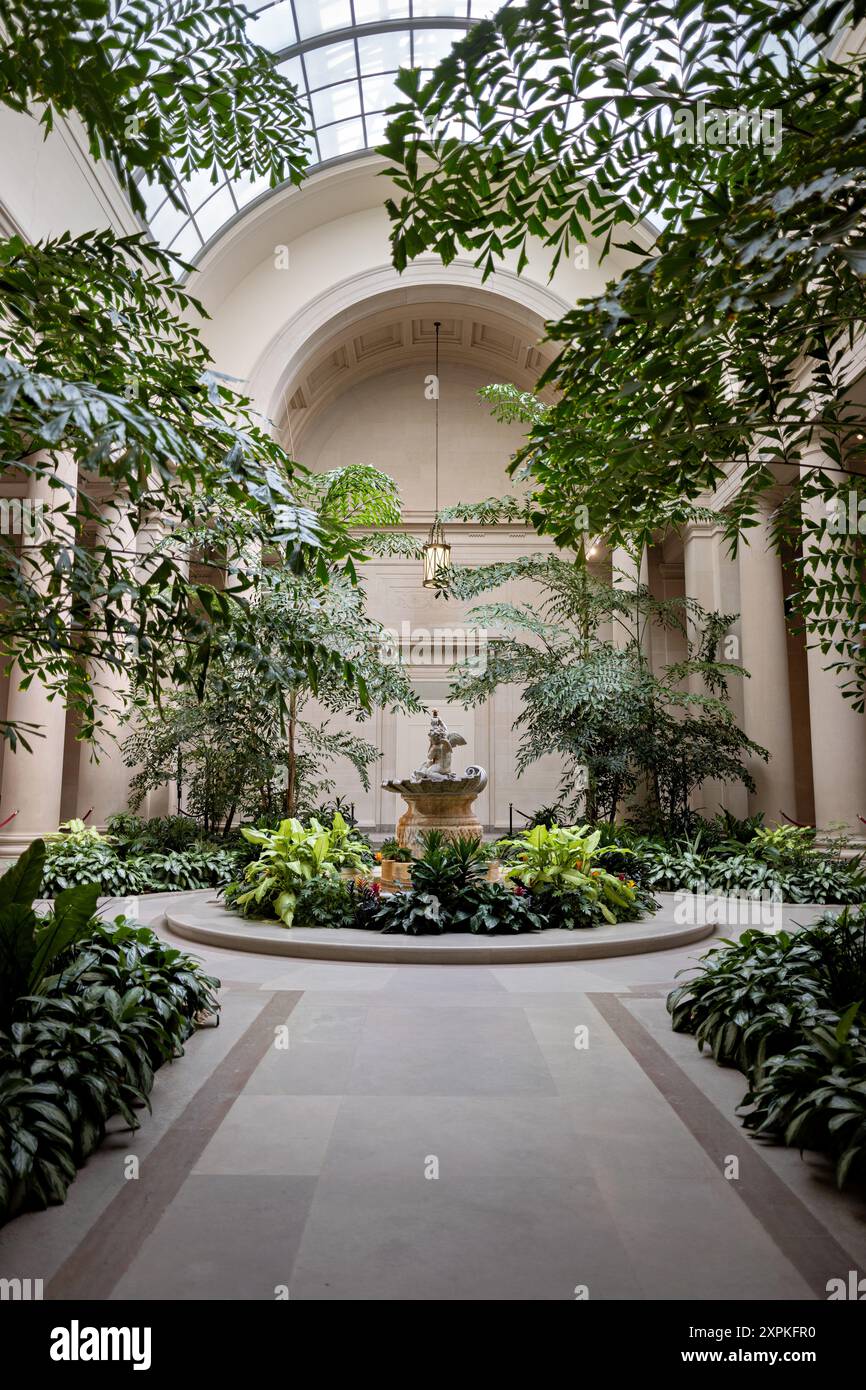 National Gallery of Art East Garden Court Washington DC // WASHINGTON DC — The East Garden Court presso la National Gallery of Art di Washington DC. Questo cortile interno neoclassico, progettato dall'architetto John Russell Pope, presenta una fontana centrale, colonne di marmo e un grande lucernario, creando uno spazio sereno per i visitatori che possono ammirare sculture e vegetazione all'interno del museo. Foto Stock