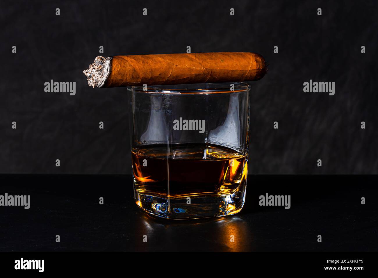 Sigaro sopra un bicchiere di whisky scozzese servito in ordine. Foto Stock