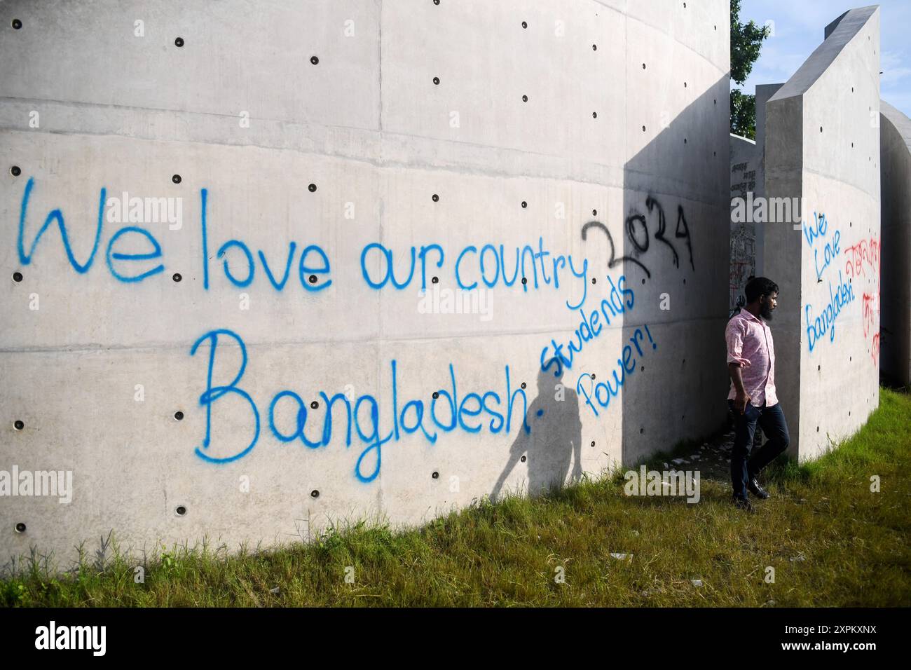 Dacca, Bangladesh. 6 agosto 2024. Un pedone si trova di fronte a un muro danneggiato in seguito a una protesta. Il 5 agosto Sheikh Hasina si dimise dalla posizione di primo ministro del Bangladesh e volò dal Bangladesh all'India. Le proteste in Bangladesh, iniziate a luglio come dimostrazioni guidate dagli studenti contro le regole di assunzione del governo, culminarono il 5 agosto, con il primo ministro in fuga e l'esercito che annunciava che avrebbe formato un governo ad interim. (Foto di Piyas Biswas/SOPA Images/Sipa USA) credito: SIPA USA/Alamy Live News Foto Stock