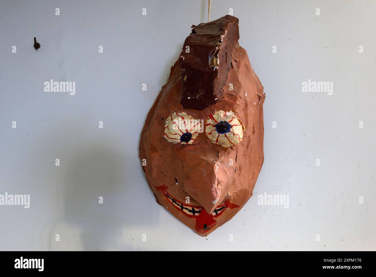 Una strana maschera appesa su un muro. Questa casa è stata demolita Foto Stock