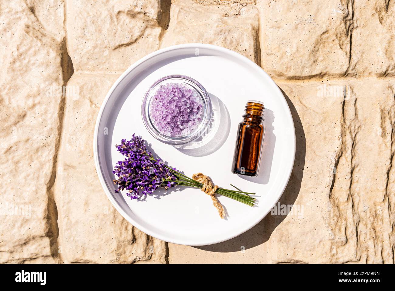 Bottiglia medica contagocce con olio di lavanda aromatico su vassoio bianco con sale di lavanda e bouquet di fiori su sfondo di pietra. centro benessere. aromaterapia. Foto Stock