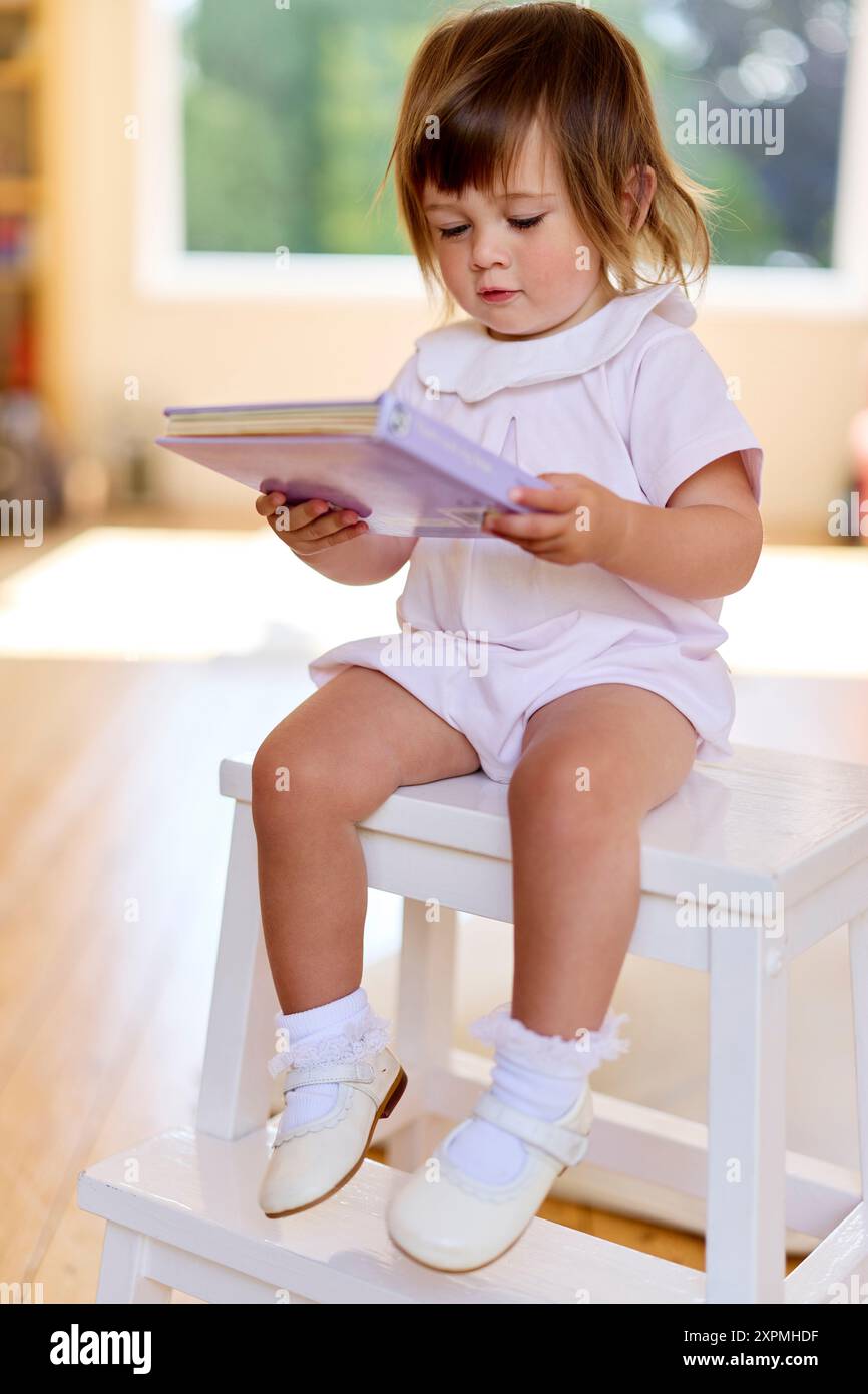 Suo figlio sedeva a leggere un libro Foto Stock