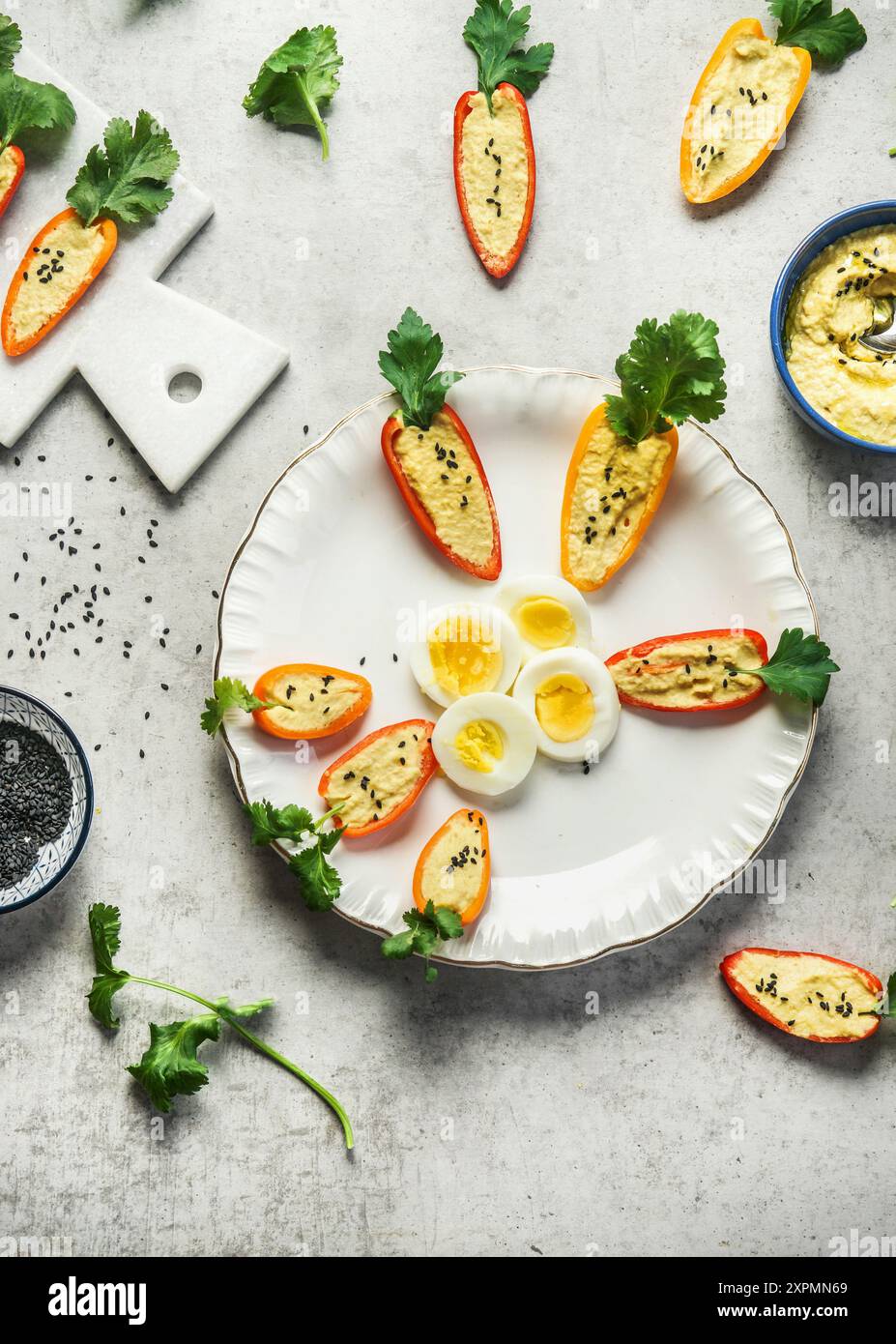 Peperoncino di paprika rossa con hummus, fatto come carote e uova a fette sul piatto, vista dall'alto Foto Stock