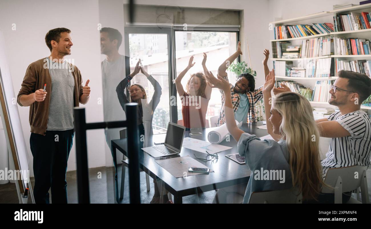 Un team aziendale felice e diversificato che celebra il successo e si diverte tutti insieme in ufficio Foto Stock