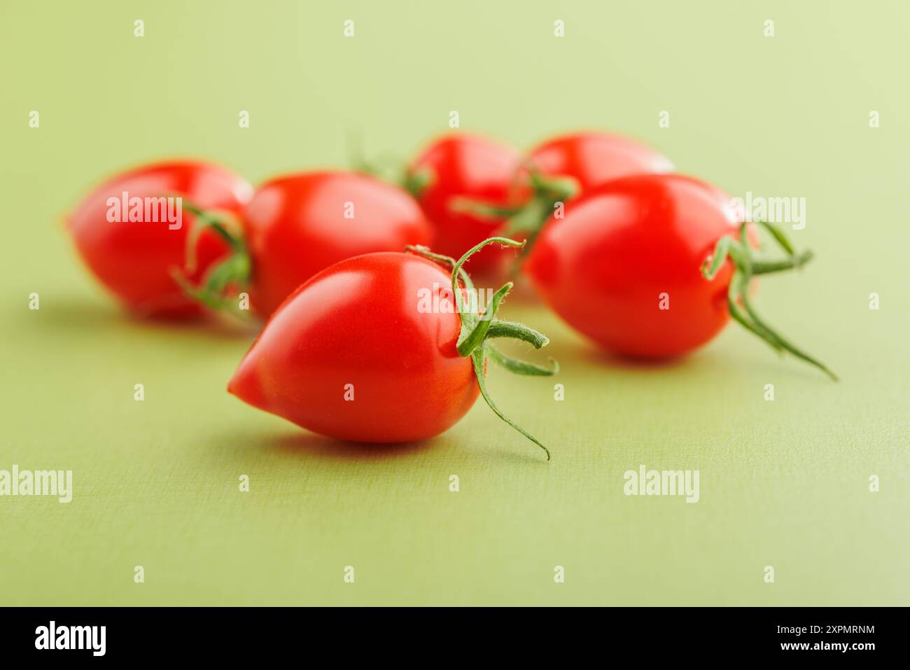 Pomodori ciliegini rossi su sfondo verde. Foto Stock