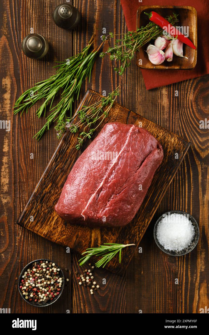 Vista ravvicinata della bistecca di manzo crudo fresco sul tavolo della cucina in legno Foto Stock