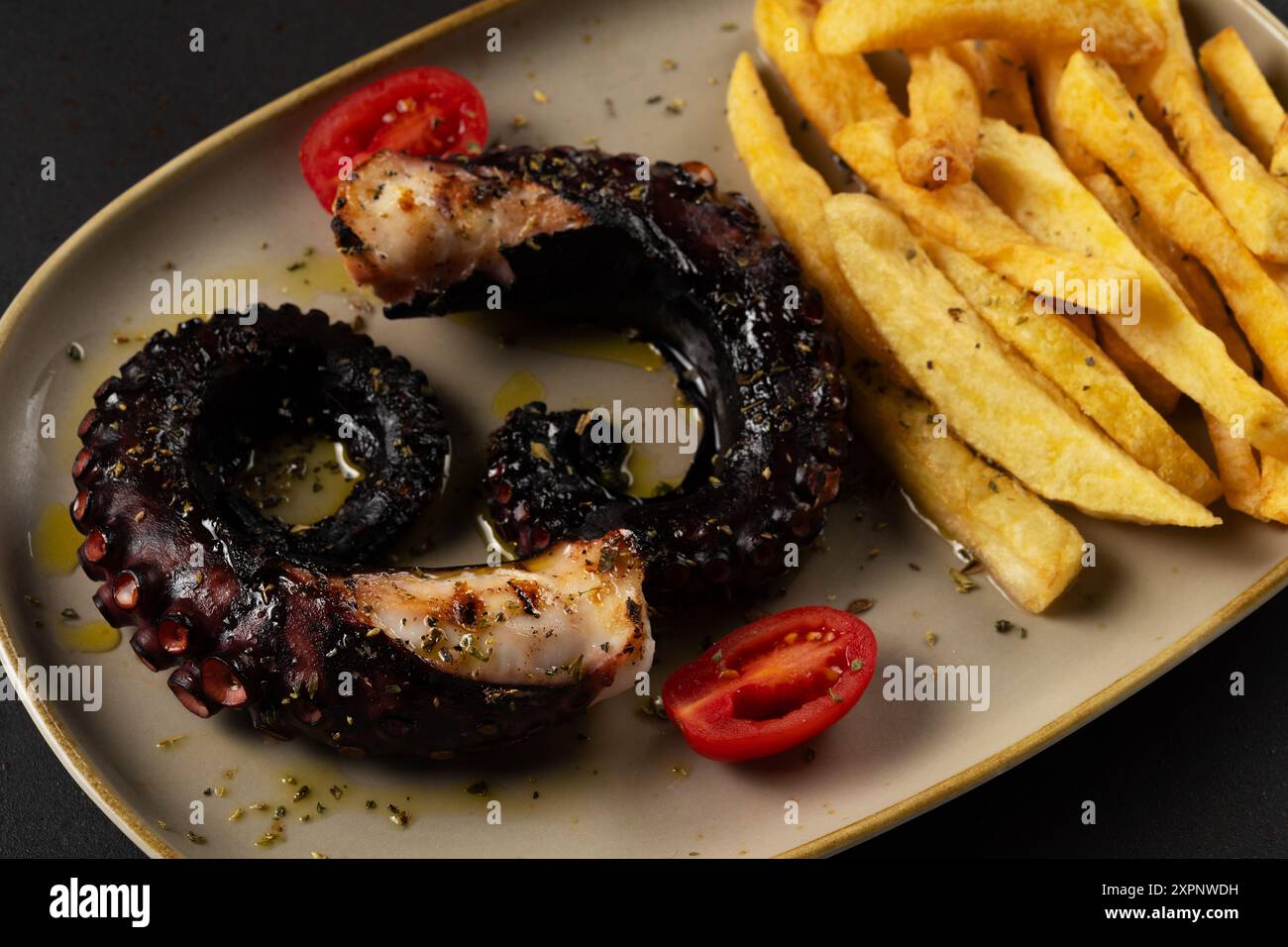 Polpo al barbecue con patate sul tavolo scuro. Sfondo di pesce. Foto Stock