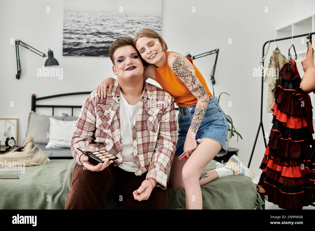 Un momento di gioia tra amici immerso in una sessione di trucco creativa in interni. Foto Stock