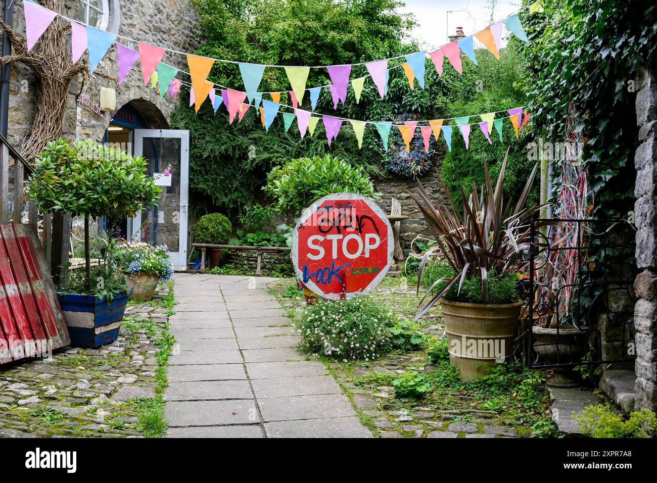 Grassington Yorkshire Regno Unito - 27 luglio 2024. Colorato cortile esterno decorato con vivaci cuccette e un giocoso cartello DI STOP, circondato da lussureggianti giardini Foto Stock