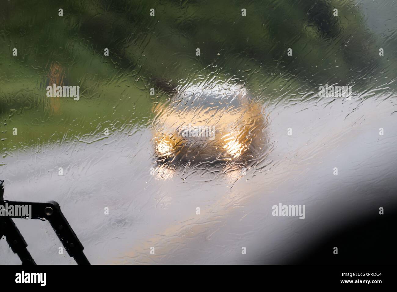 Pioggia intensa, taxi giallo visibile dietro il parabrezza bagnato con tergicristallo Foto Stock