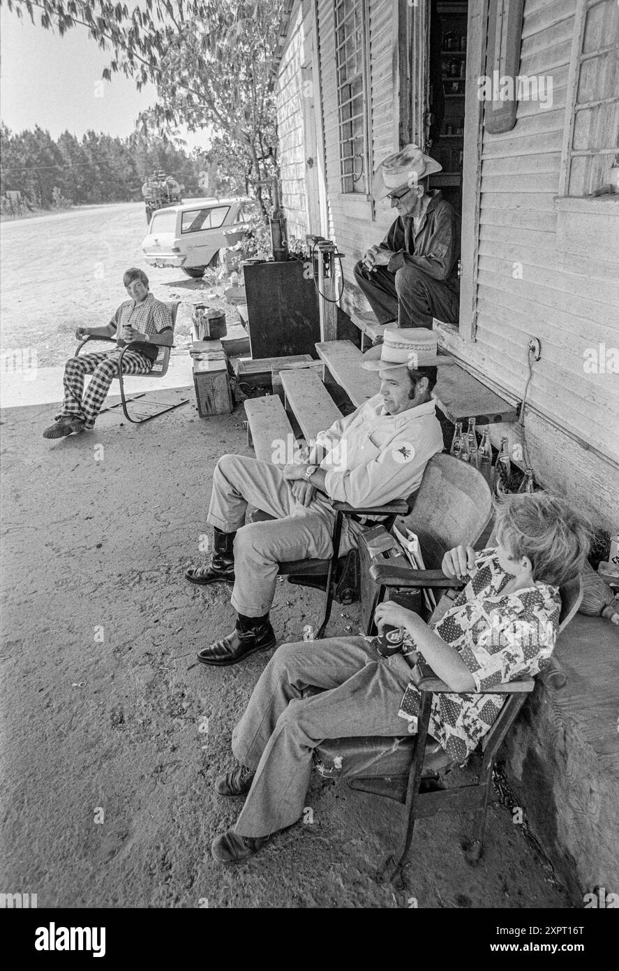 Macedonia, Arkansas, Stati Uniti – 23 giugno 2024: Tiro verticale di uomini e ragazzi che parlano fuori da un negozio di campagna dell'Arkansas degli anni '1970. Foto Stock