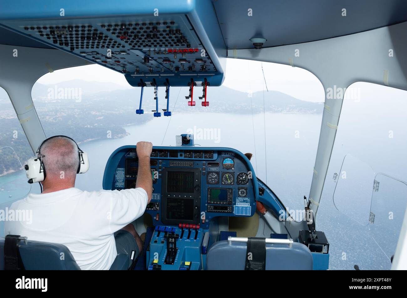 Un pilota che naviga nella cabina di pilotaggio di un dirigibile Zeppelin NT, godendo di una vista panoramica sul paesaggio francese. Il dirigibile è un dirigibile multiuso pieno di elio noto per i suoi voli lussuosi e tranquilli. Foto Stock