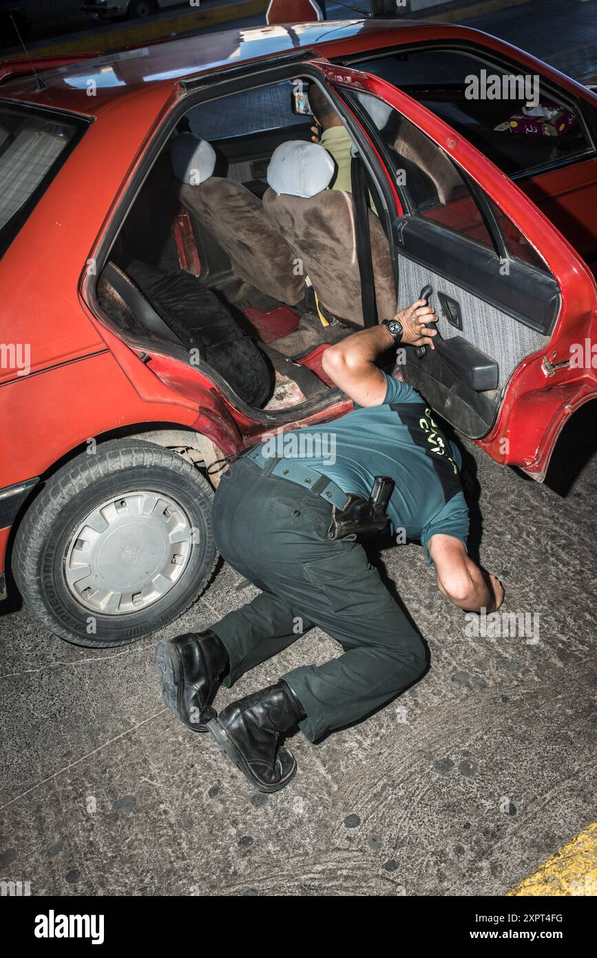 Funzionario della sicurezza di frontiera che ispeziona un'automobile per i migranti clandestini al valico di frontiera dell'Unione europea a Melilla, giugno 2012. L'immagine raffigura l'agente che controlla accuratamente il veicolo. Foto Stock