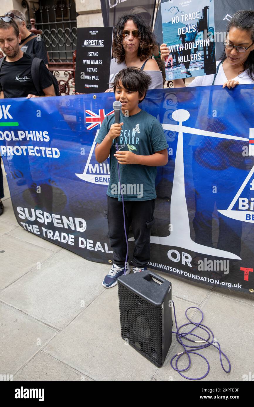 Un ragazzino che usa un microfono fa un discorso davanti a uno striscione di protesta.durante TA, un ragazzino fa un discorso usando un microfono durante una dimostrazione.si raduna. I sostenitori dell'attivista anti-baleniera Paul Watson tennero una manifestazione fuori dal Foreign and Commonwealth Office a Westminster, nel centro di Londra. Il piccolo gruppo di manifestanti chiede il suo immediato rilascio. Il fondatore e co-fondatore di Greenpeace è stato arrestato in Groenlandia con un mandato di arresto internazionale e ora sta per essere deportato in Giappone. Il settantacinquenne fu accusato di aver violato e aggredito un Giappone Foto Stock