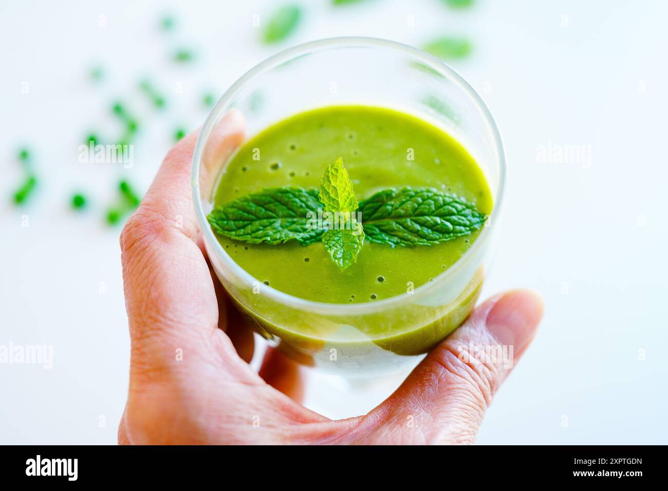 Donna che beve frullato verde con verdure biologiche su sfondo bianco Foto Stock