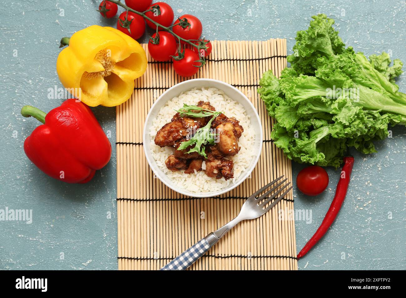 Gustoso pollo agrodolce con riso nel recipiente, tappetino e verdure su fondo grunge turchese Foto Stock