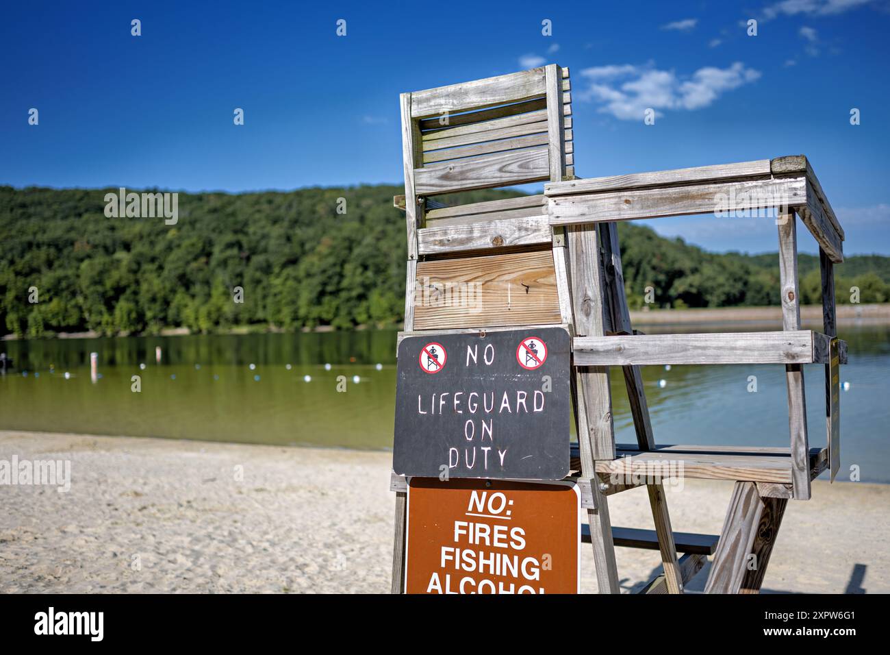 Bagnino Stand No bagnino in servizio cartello Greenbrier Lake Boonsboro Maryland // BOONSBORO, Maryland, Stati Uniti - un vecchio banco bagnino in legno con un cartello "No bagnino in servizio" presso il lago Greenbrier vicino a Boonsboro, Maryland. Questa scena estiva cattura il fascino rustico della zona del lago in una giornata di sole, con le calme acque del lago visibili sullo sfondo. Foto Stock