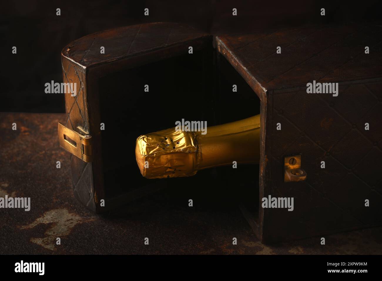 Una bottiglia di champagne in una scatola regalo in legno ricoperto di pelle, sigillata, con una forte luce laterale calda. Foto Stock