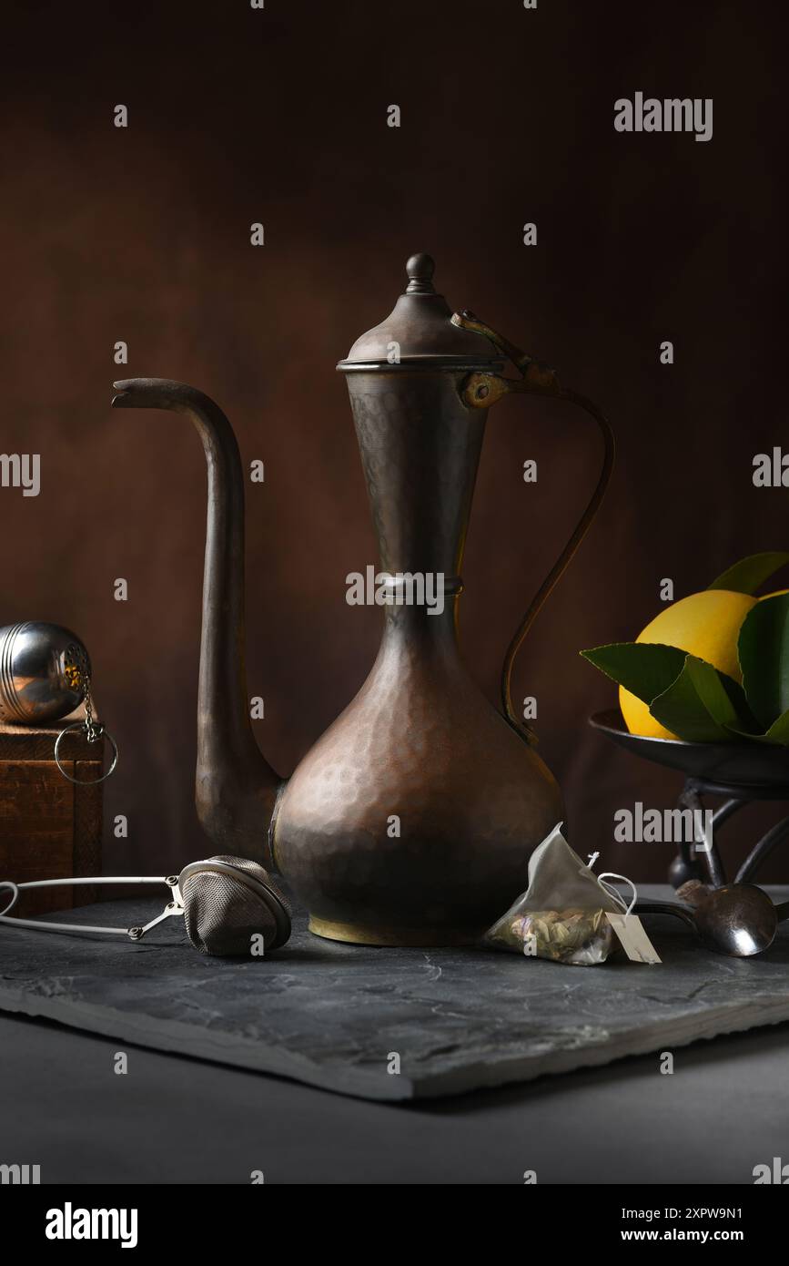Tea Pot e limoni STILL Life, con infuocatori e bustina di tè. Luce laterale calda e intensa. Foto Stock