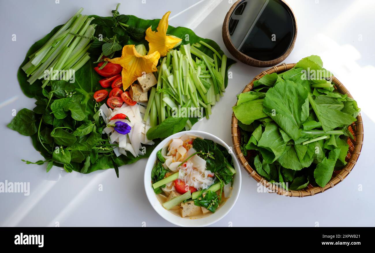 Vibrante pasto vietnamita su foglia verde con materie prime fresd come pomodori a fette, fiori di zucca, citronella, verdure per cibo vegano sano Foto Stock