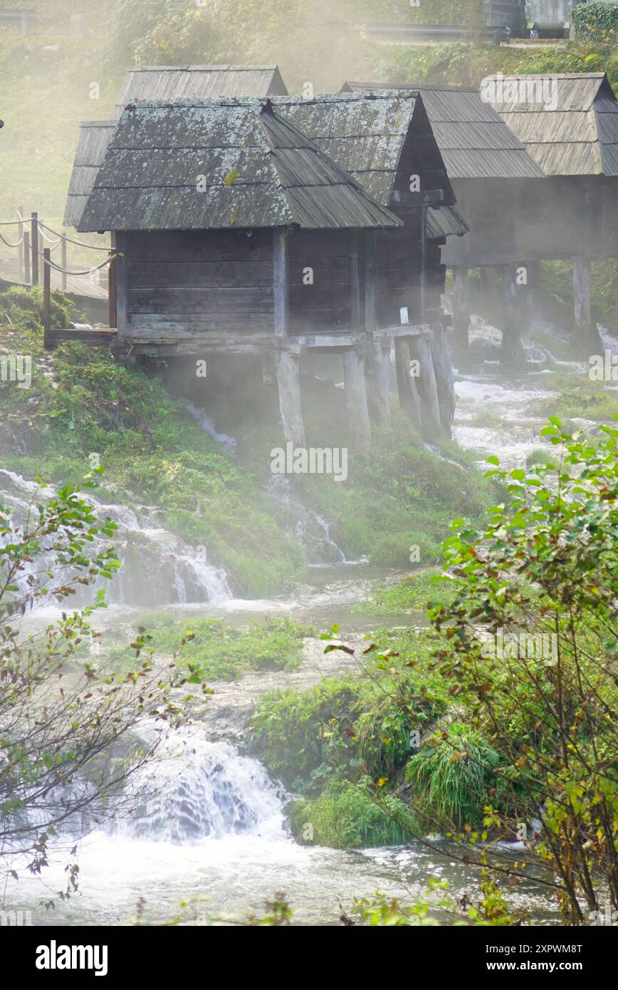 Vista dei tradizionali mulini ad acqua costruiti vicino a Jajce sul lago Pliva, Bosnia ed Erzegovina. Splendido paesaggio con edifici in legno, acqua e nebbia Foto Stock