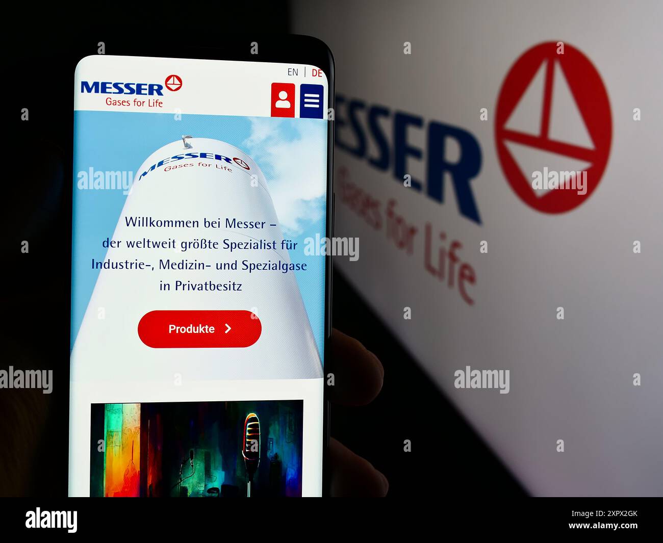 Persona che detiene un cellulare con pagina web della società tedesca di gas industriali Messer se Co.. KGaA davanti al logo. Messa a fuoco al centro del display del telefono. Foto Stock