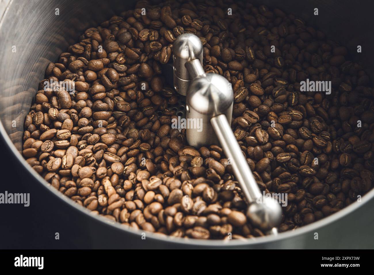 Vista ravvicinata della torrefazione dei chicchi di caffè in un tostapane a tamburo piccolo Foto Stock