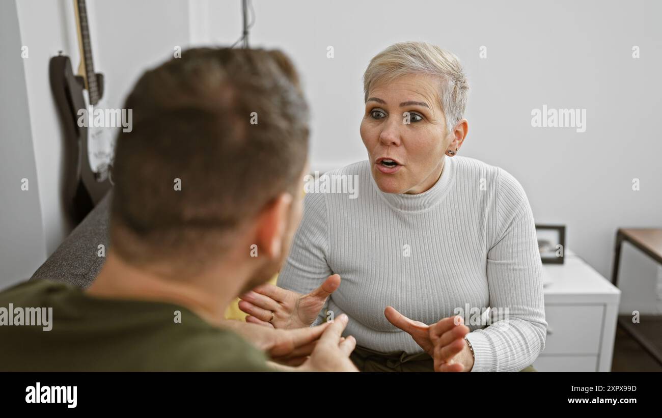 Una donna e un uomo conversano seriamente in un salotto moderno, riflettendo il dialogo familiare degli adulti in casa. Foto Stock