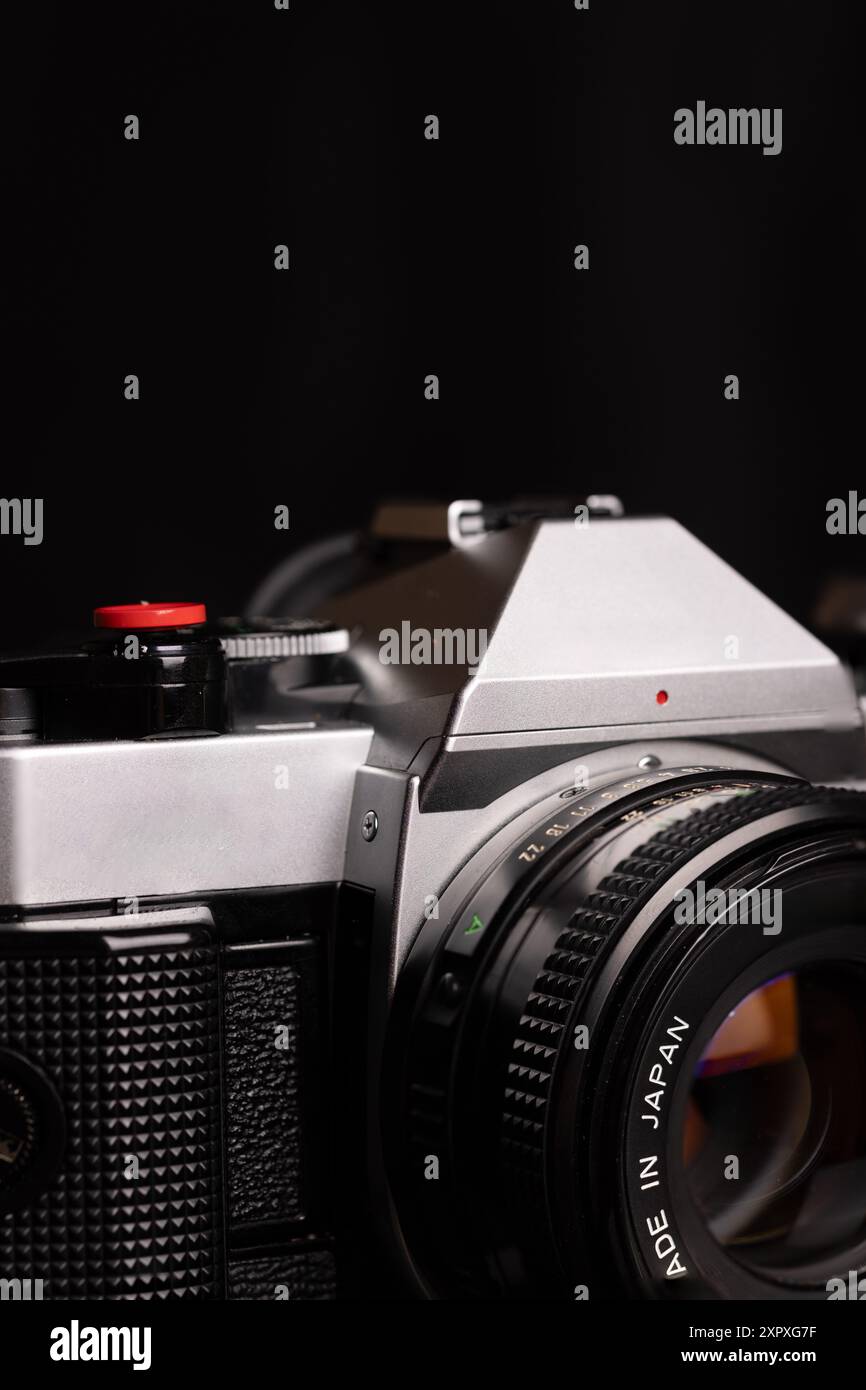 Primo piano verticale di una vecchia videocamera su sfondo nero. I dettagli intricati della fotocamera e il fascino vintage sono messi in risalto. Foto Stock
