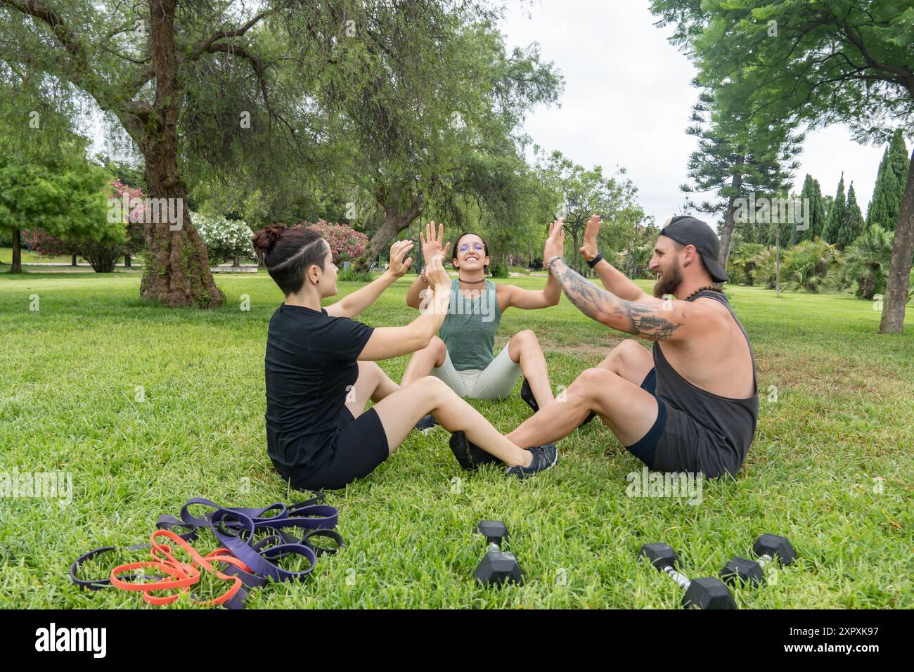 Un gruppo di amici partecipa a una sessione di allenamento in un ambiente naturale. Perfetto per i contenuti che mettono in risalto gli esercizi di gruppo e gli allestimenti all'aperto Foto Stock