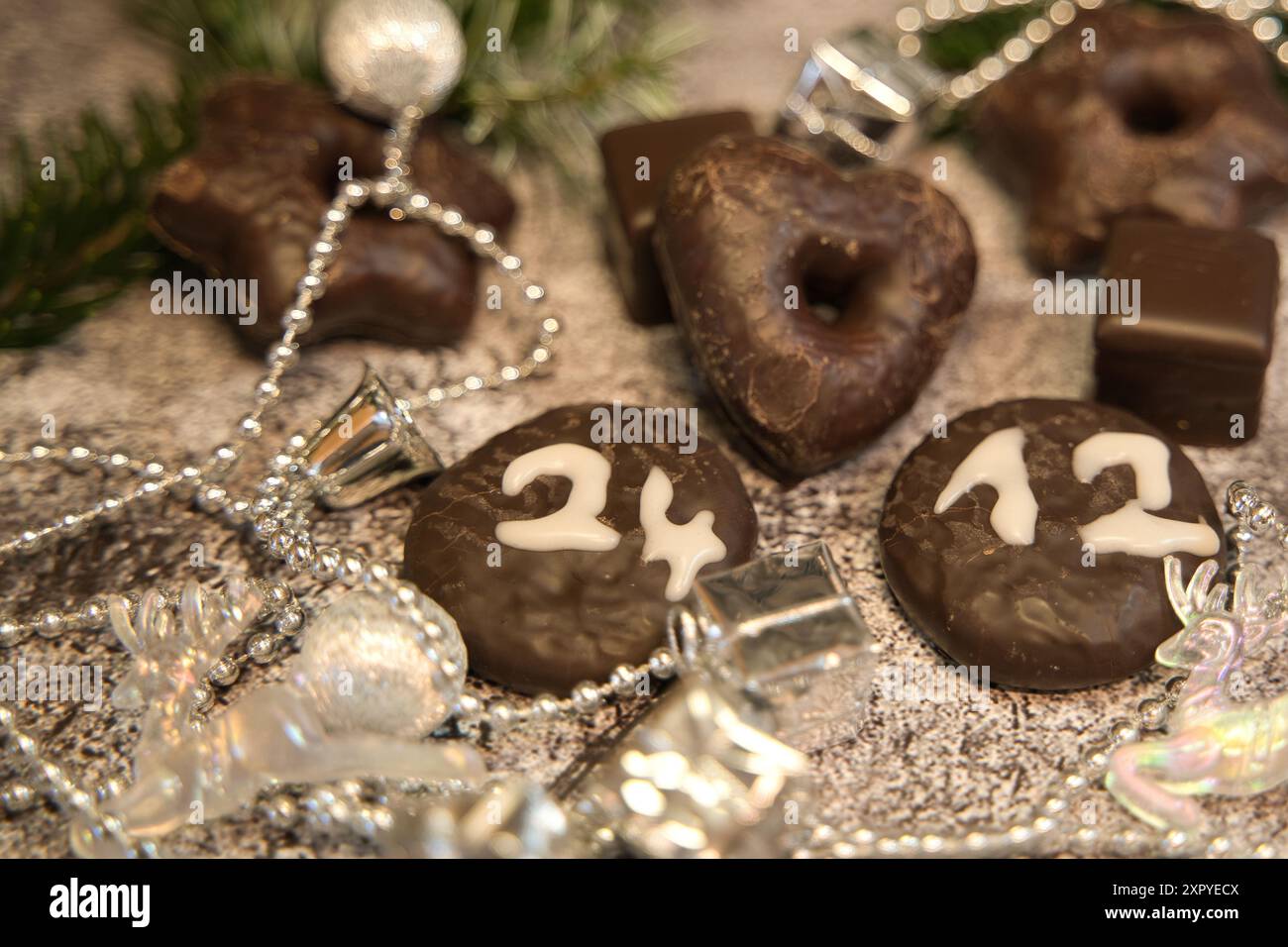Biscotti al cioccolato con la data della vigilia di Natale davanti alle decorazioni natalizie Foto Stock