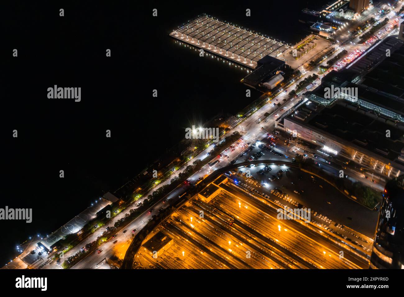 Vista aerea con banchine industriali e stazione ferroviaria con treni. Panorama della zona da un elicottero, che mostra gli edifici industriali e le attrezzature per il carico del porto Foto Stock