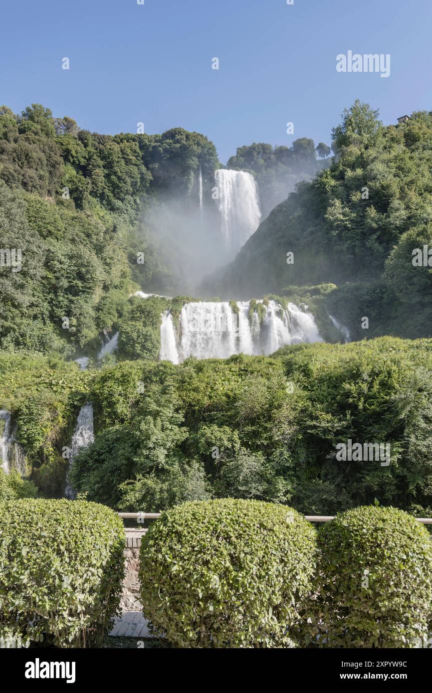 Paesaggio con alte cascate in mezzo a una lussureggiante vegetazione verde, fotografato dal basso con la luminosa luce estiva a Marmore, Umbria, Italia Foto Stock