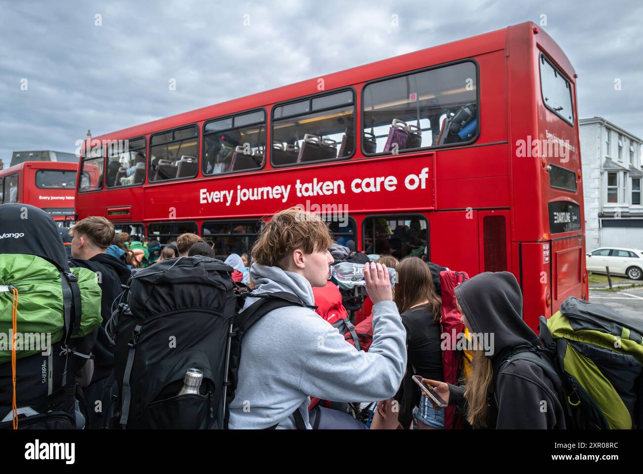 I giovani fanno la fila per salire a bordo degli autobus per portarli al Boardmasters Festival Newquay in Cornovaglia nel Regno Unito. Foto Stock
