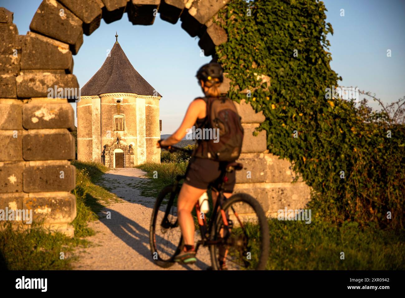 Turista donna, ciclista in gita in bicicletta, esplorando la regione di Dolenjska e guardando la Torre del Diavolo nel villaggio di Soteska vicino al fiume Krka, in Slovenia Foto Stock