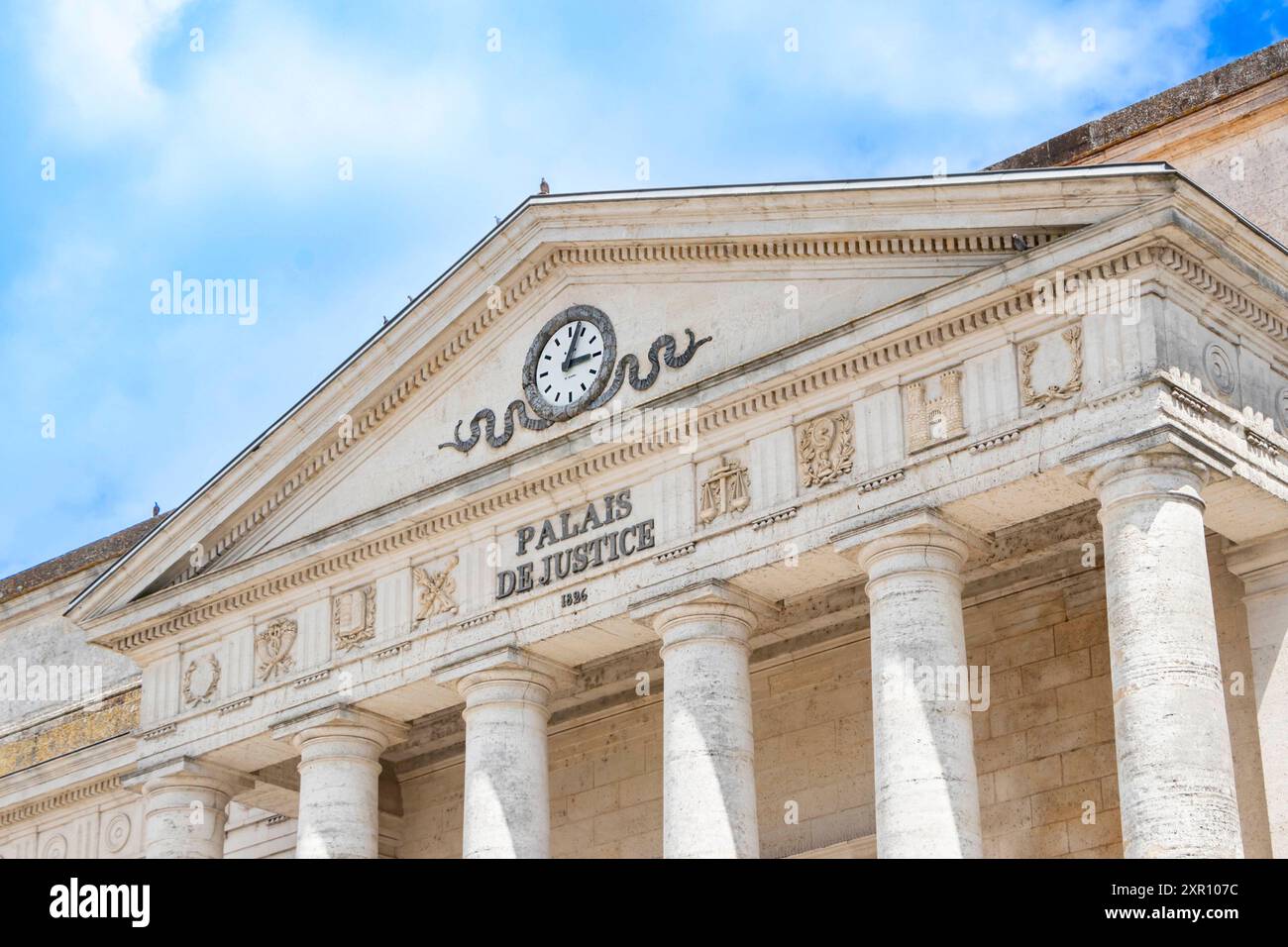 Edificio storico del tribunale con colonne classiche e un orologio sulla sua facciata sotto un cielo blu. Foto Stock