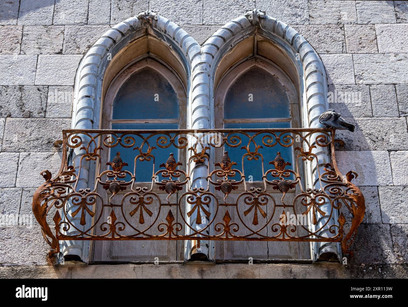 finestre ad arco in vecchio stile gotico con ringhiere arrugginite del balcone. Foto Stock