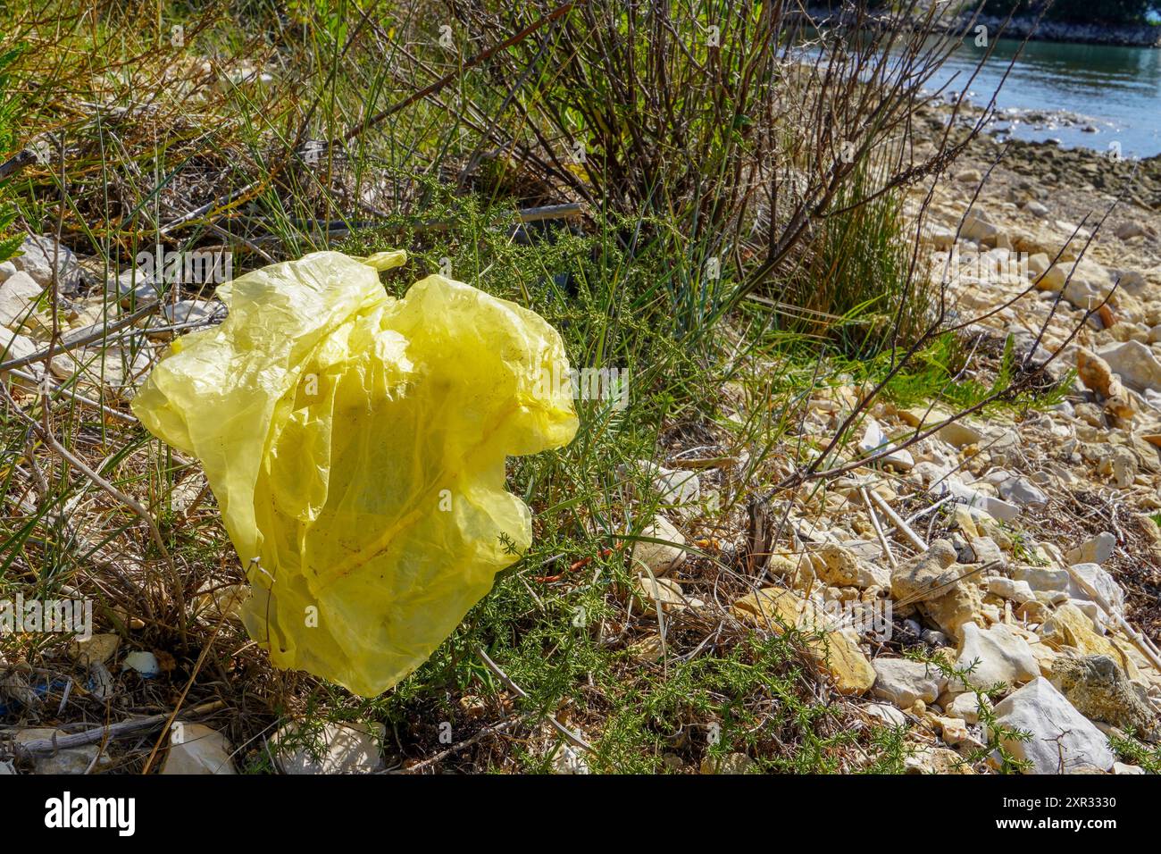 Sacchetto di plastica gettato sulla spiaggia sabbiosa, problema ambientale. Foto Stock