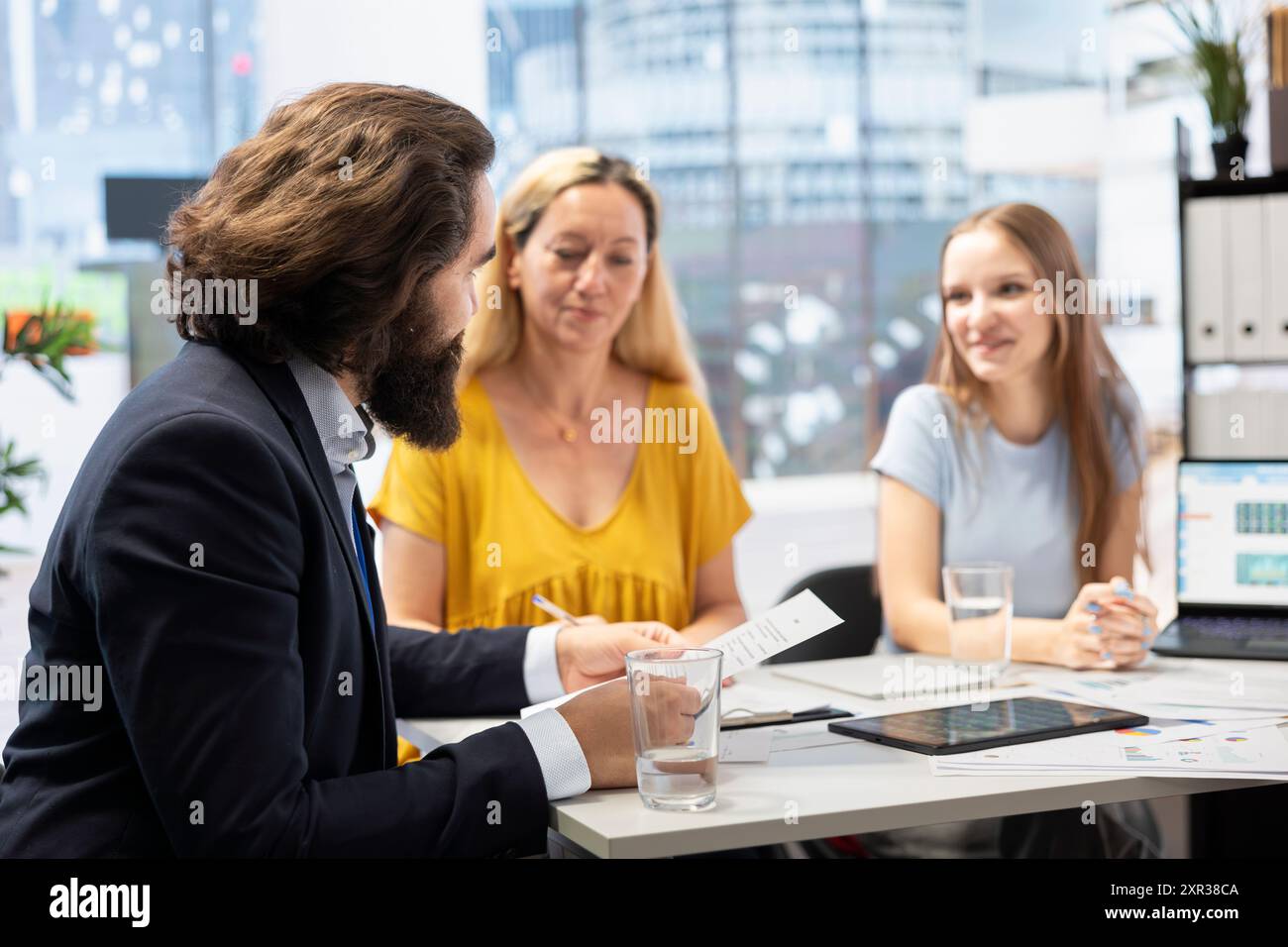 Consulente finanziario che calcola il patrimonio netto dei clienti, prendendo in considerazione attività e passività. Consulente in ufficio che aiuta i clienti a decidere quanto denaro investire, sviluppando il budget Foto Stock