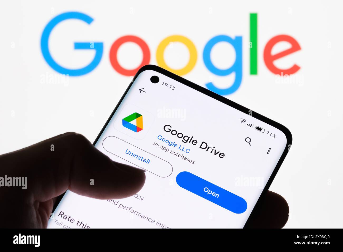 Primo piano dello schermo di uno smartphone che visualizza l'app Google Drive con il logo Google sullo sfondo, che illustra la connessione tra Google Drive e G. Foto Stock