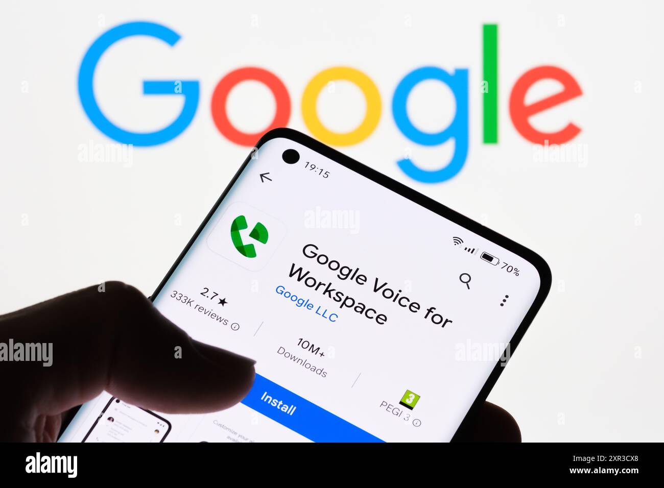 Primo piano dello schermo di uno smartphone che visualizza l'app Google Voice for Workspace con il logo Google sullo sfondo, che mostra il collegamento tra Google Voice per Foto Stock