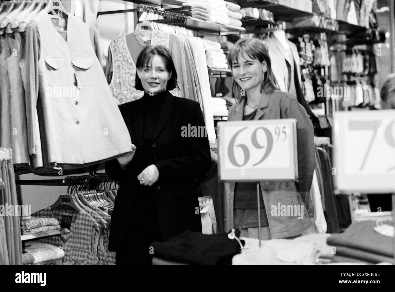 Due donne in un negozio di abbigliamento femminile, Whizgle Dutch News: Immagini storiche su misura per il futuro. Esplora il passato dei Paesi Bassi con prospettive moderne attraverso le immagini delle agenzie olandesi. Colmare gli eventi di ieri con gli approfondimenti di domani. Intraprendi un viaggio senza tempo con storie che plasmano il nostro futuro. Foto Stock