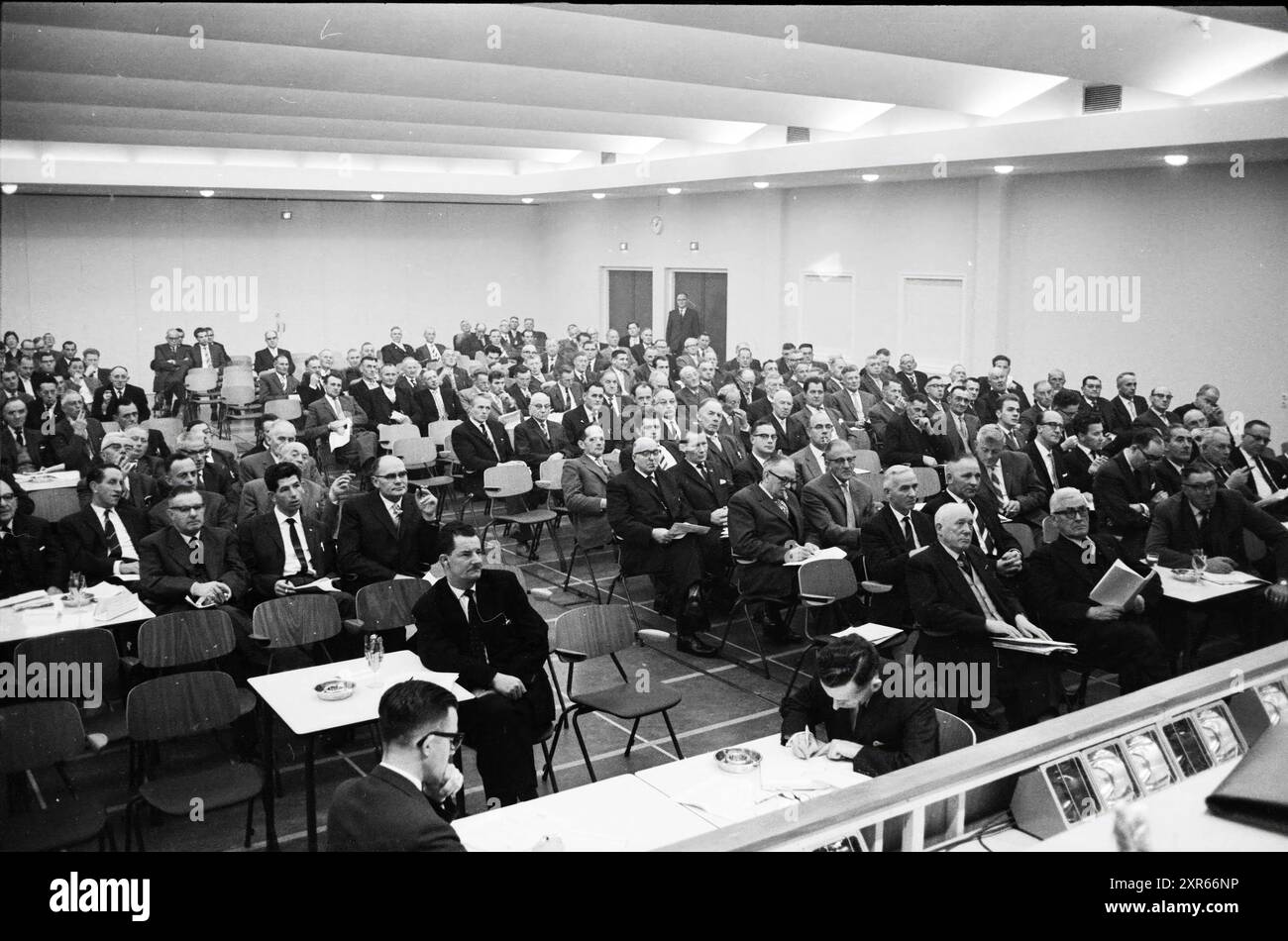 Forum di otto uomini si rivolge a una stanza piena di uomini, Whizgle Dutch News: Immagini storiche su misura per il futuro. Esplora il passato dei Paesi Bassi con prospettive moderne attraverso le immagini delle agenzie olandesi. Colmare gli eventi di ieri con gli approfondimenti di domani. Intraprendi un viaggio senza tempo con storie che plasmano il nostro futuro. Foto Stock