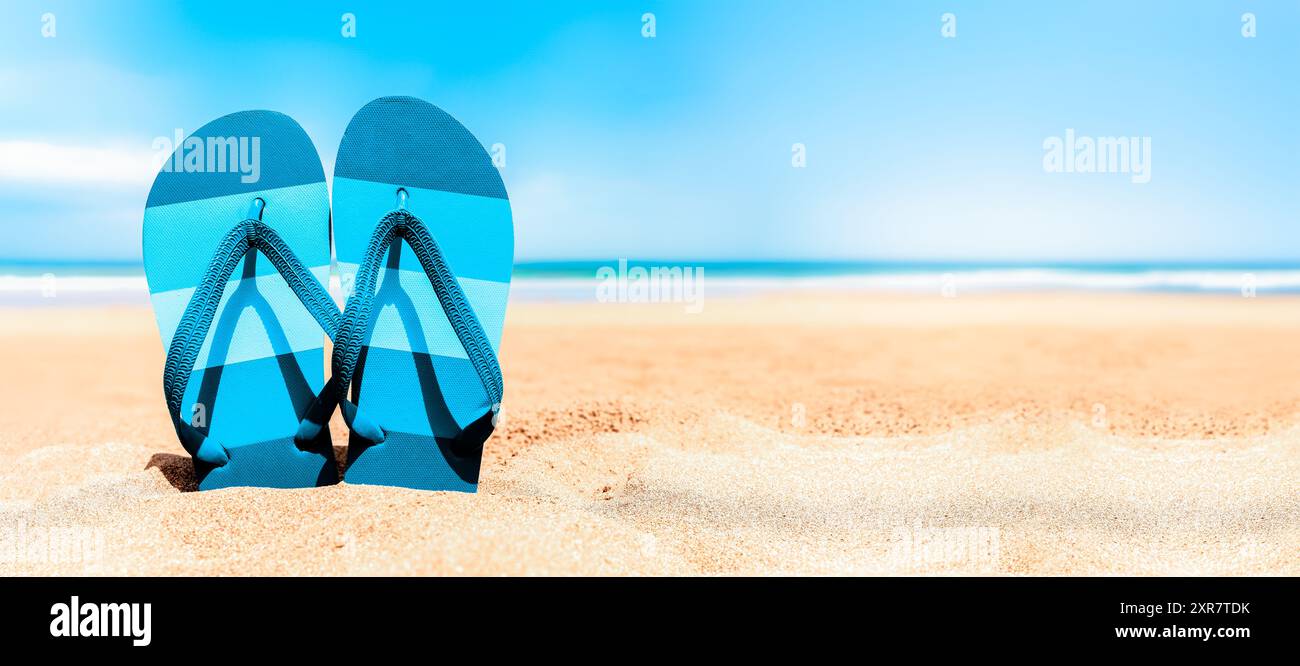Infradito sulla spiaggia di sabbia in una giornata di sole - sfondi per le vacanze estive in spiaggia Foto Stock