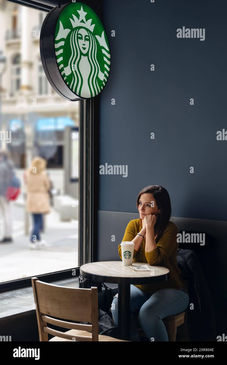 MADRID, SPAGNA - 8 APRILE 2021: Donna che fa una pausa all'interno dello Starbucks Coffee Shop nel centro di Madrid. Foto Stock