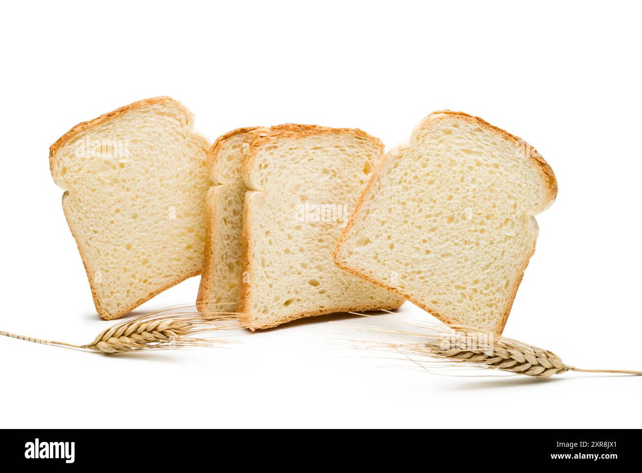 Fette di pane bianco con orecchie di grano su sfondo bianco. Foto Stock