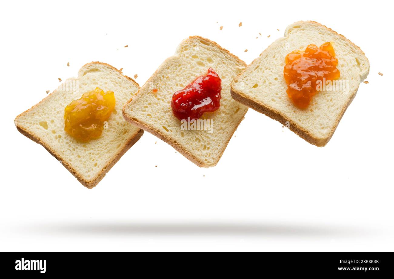 Fette di pane bianco con varietà di marmellate che volano su sfondo bianco. Foto Stock