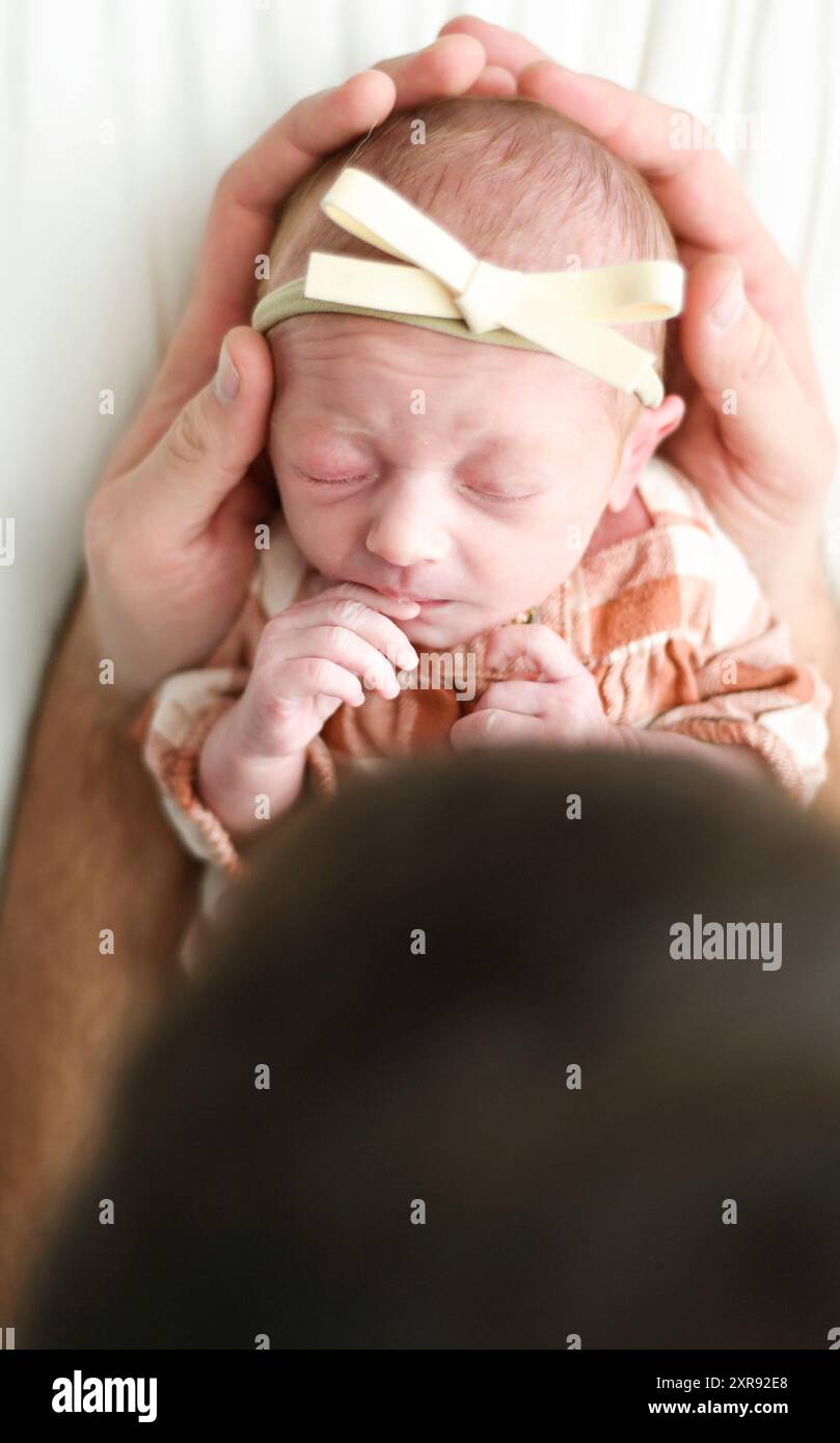Neonato in un abito a scacchi di pesca con archetto giallo Foto Stock