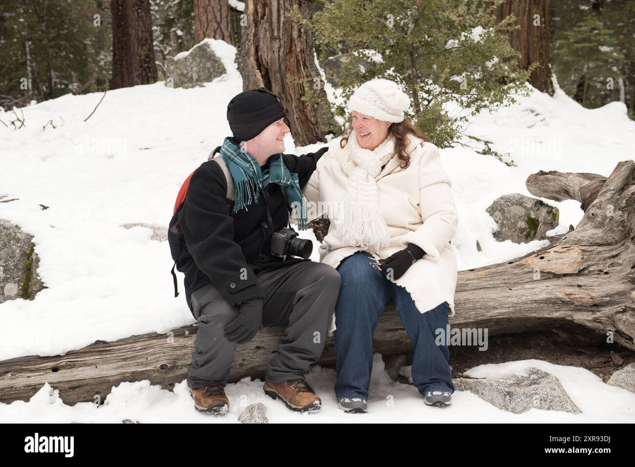 Madre e figlio seduti su un tronco insieme nella neve Foto Stock